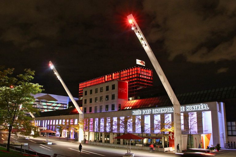 Red and purple lit museum building against a dark night sky in Montreal.