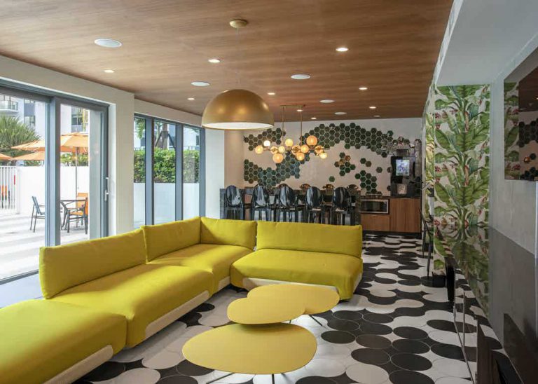 Colorful living setting with yellow sofa, wooden accents, and black and white floor.