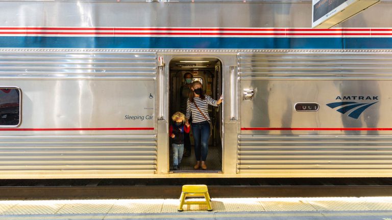 Passengers stepping off a silver colored train.