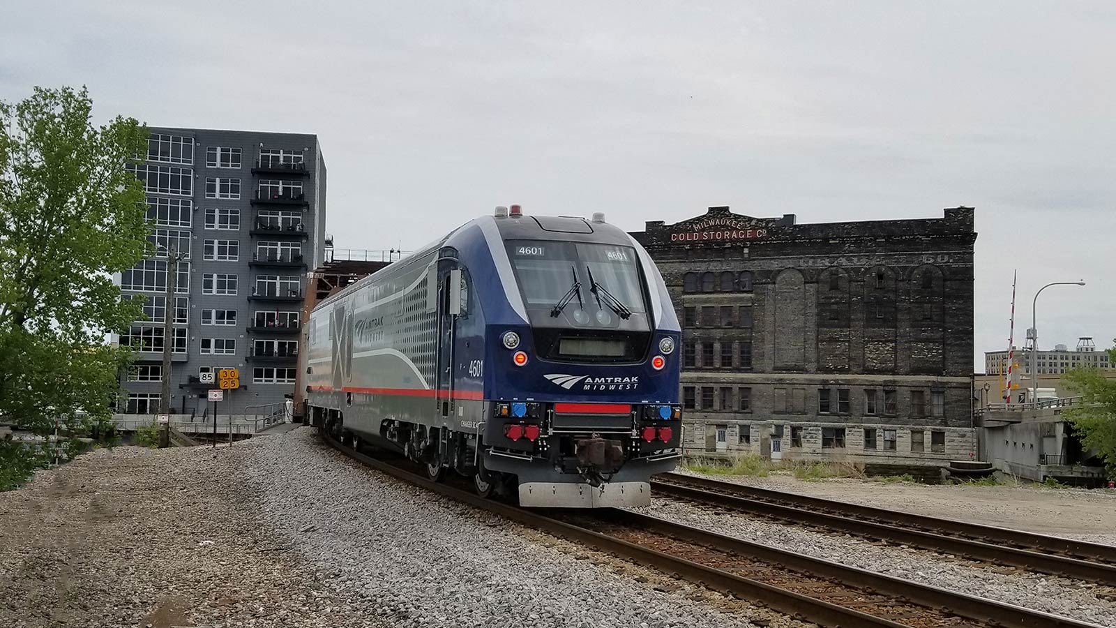 Blue and silver train departing city.