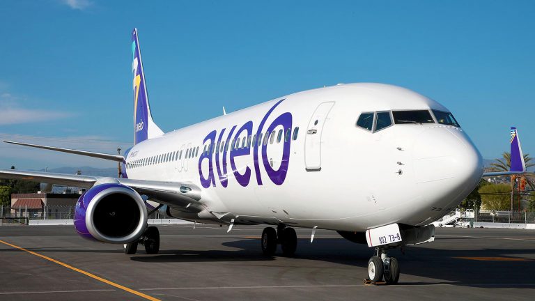 White plane with purple letting at airport.