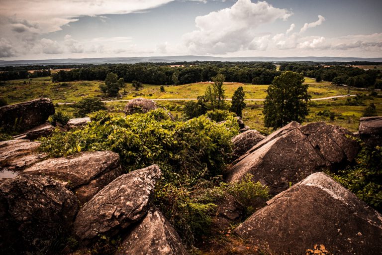 Green rolling hills against dark colored rock formations.