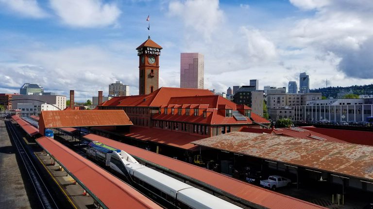 Red roofed train station against a modern city skyline.