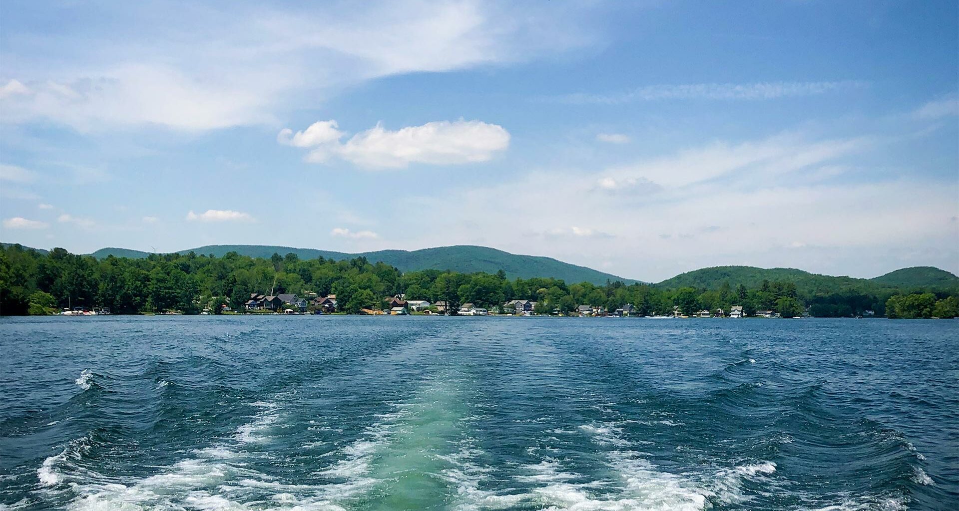 Green hills against the blue waters of a lake and sky.