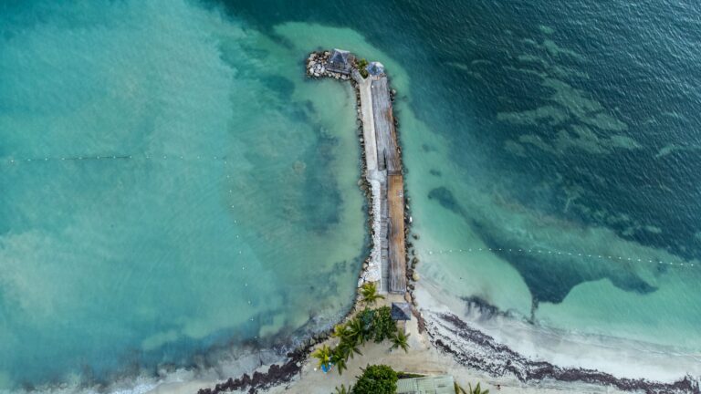 Crystal clear waters in Jamaica with a body of land extending into the waters.