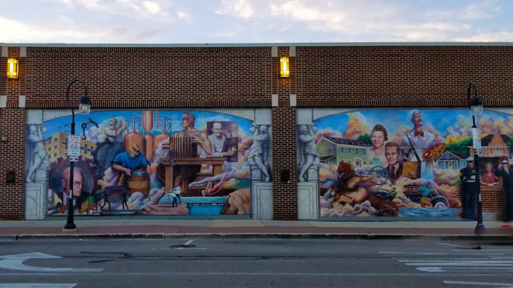 Colorful mural depicting Naperville throughout the years on the side of a brick building.