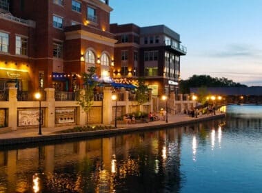 Multi-story residential building reflecting on the riverwalk next to the building during the sunset.